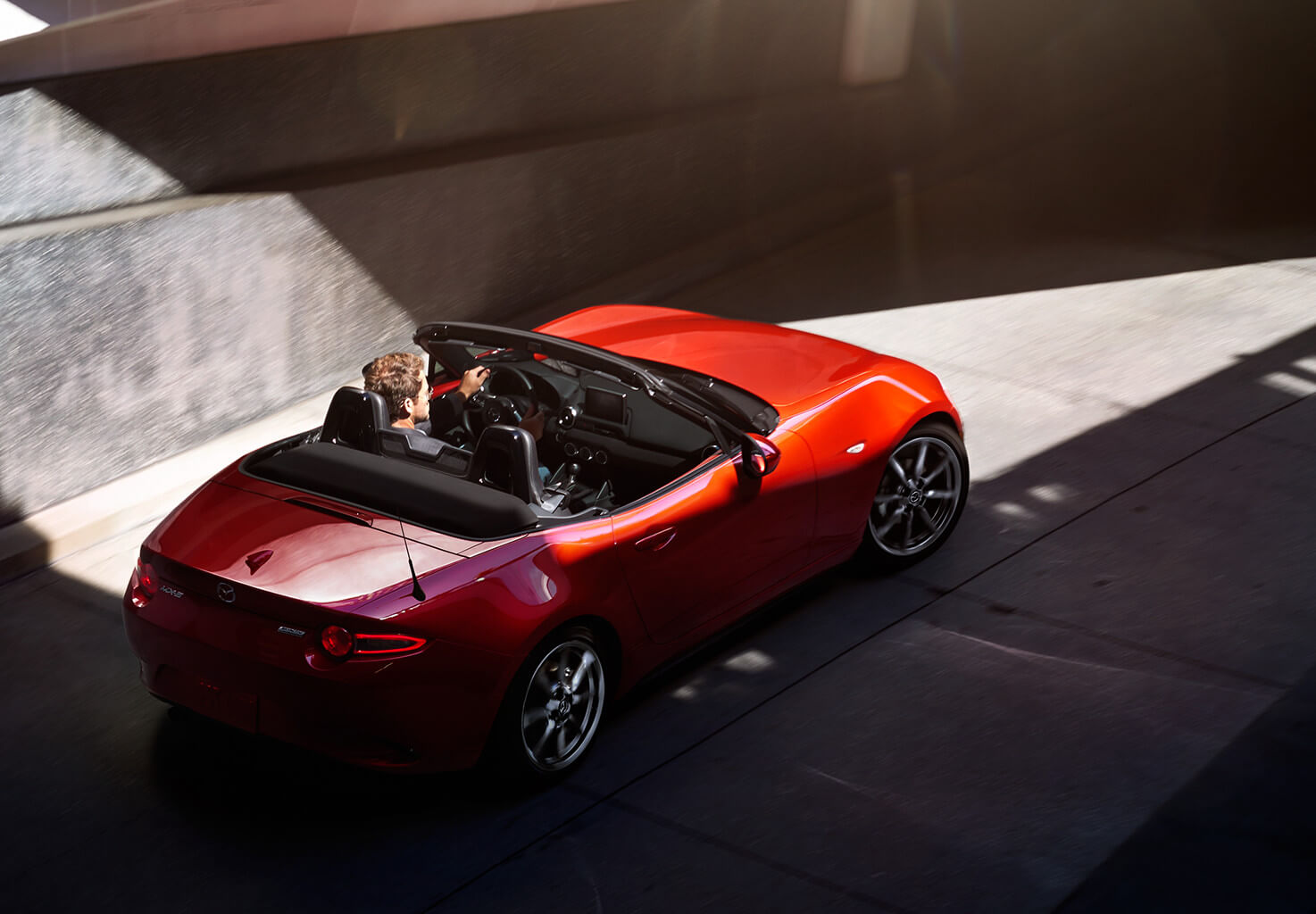 A sporty red mazda being driven underneath a tunnel