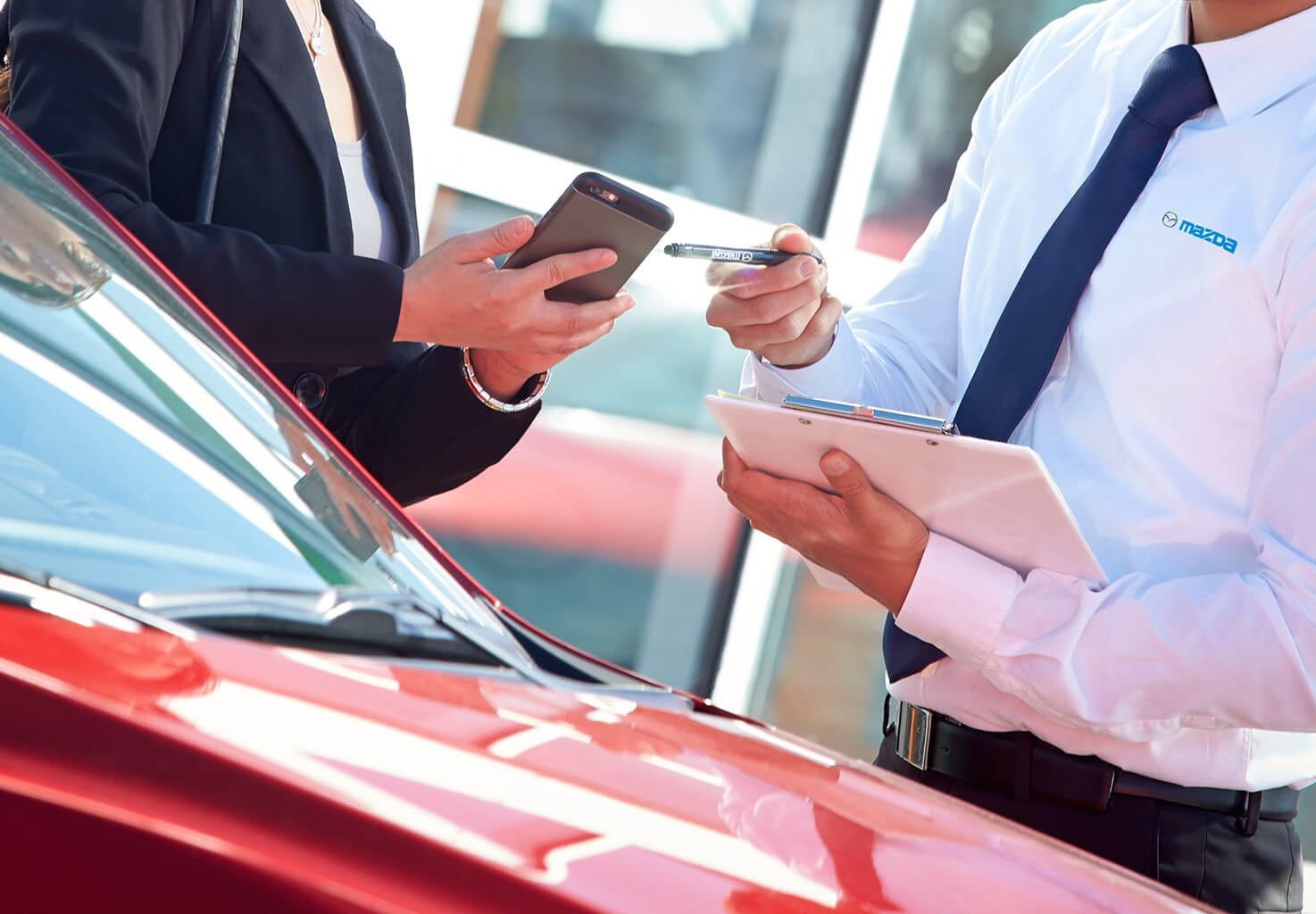 two people making a business deal in front of a red mazda