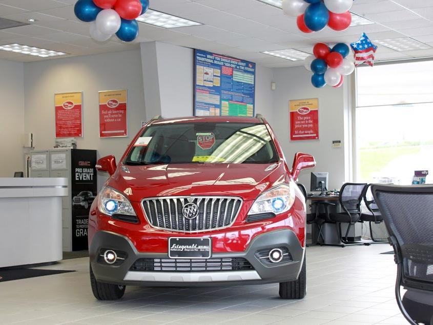 Two women looking at a tablet next to a new car.