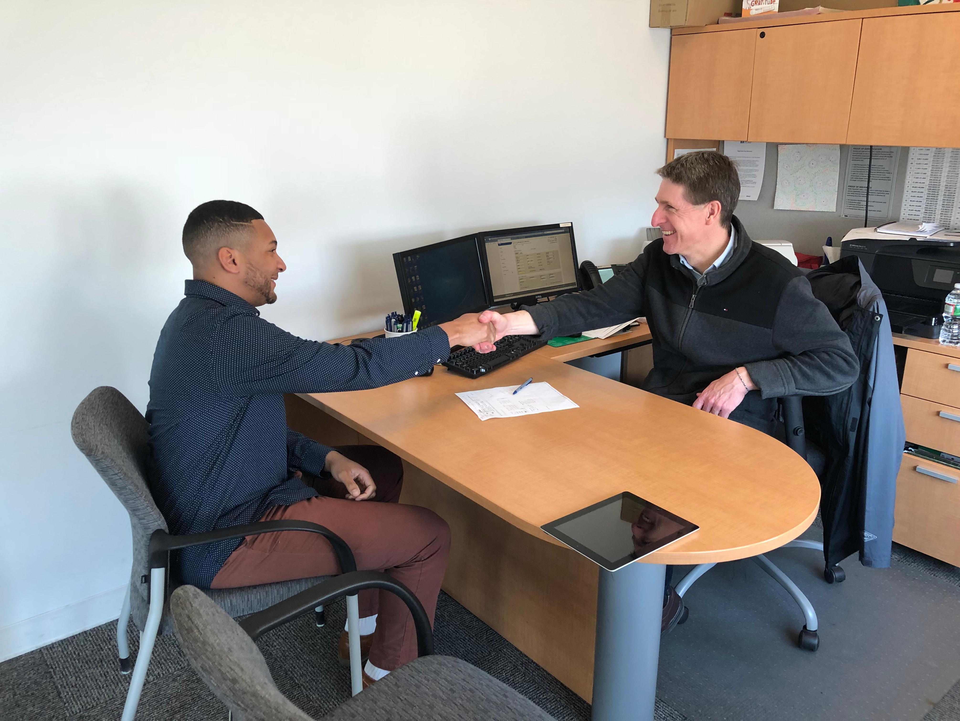Woman at a customer service desk helping a man with a transaction.