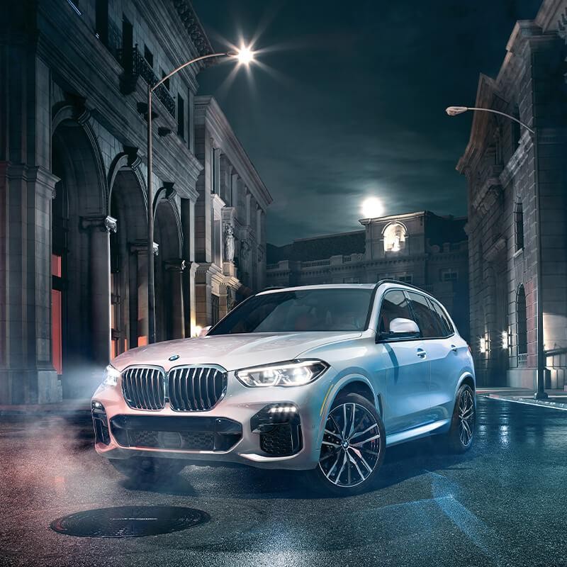 Front view of a BMW X5 parked on a city street on a foggy night