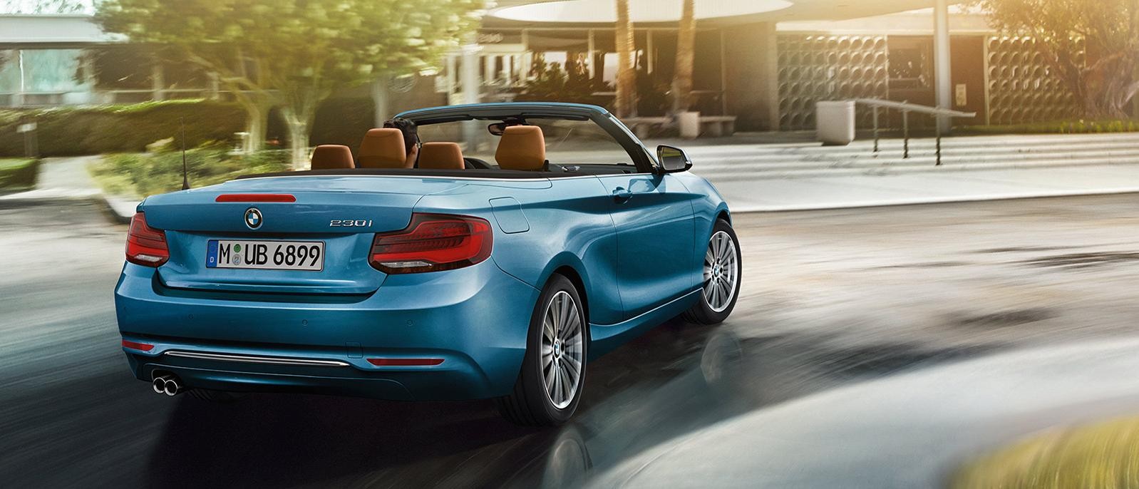 A blue BMW 2 Series Convertible driving down the road.