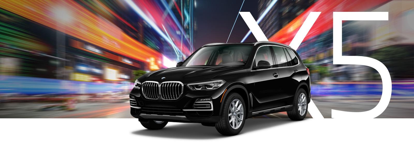 A black BMW X5 on a city street at night with streaks of light.