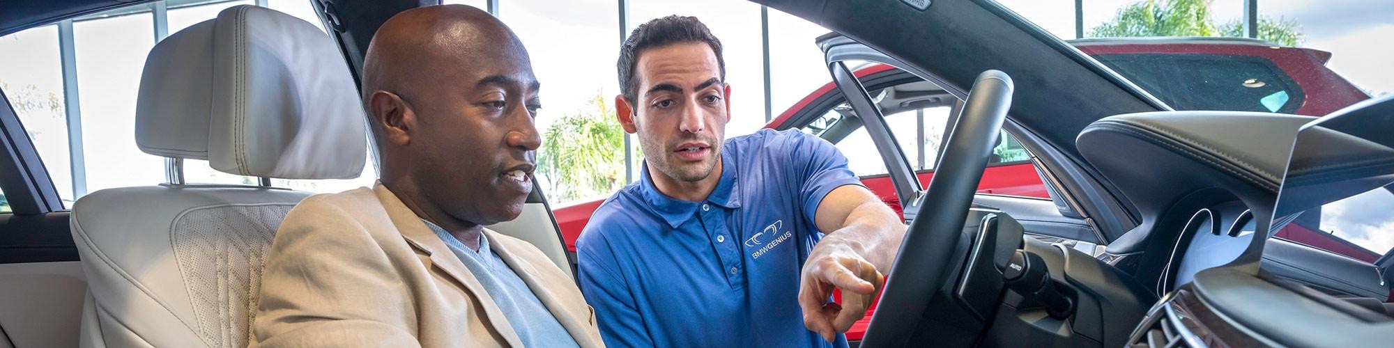 A BMW sales associate shows a customer feature in a vehicle.