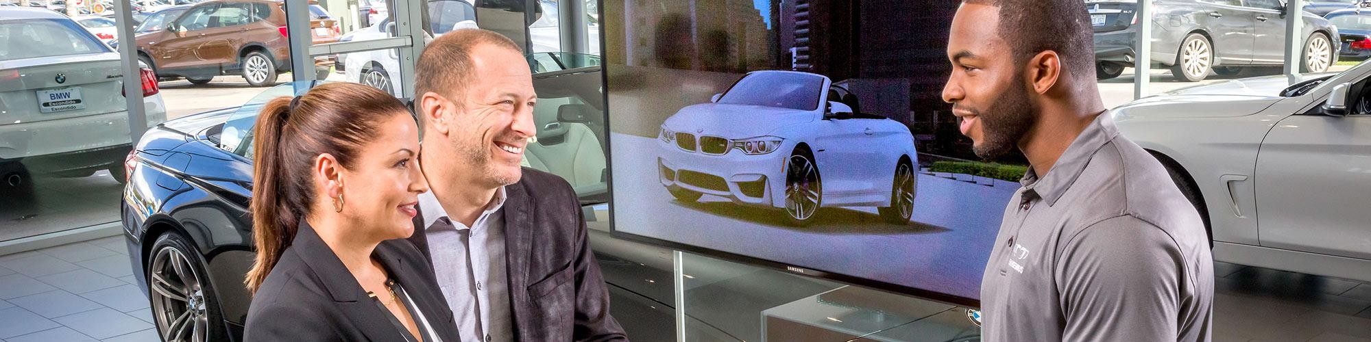 A BMW sales associate working with a couple in the showroom.