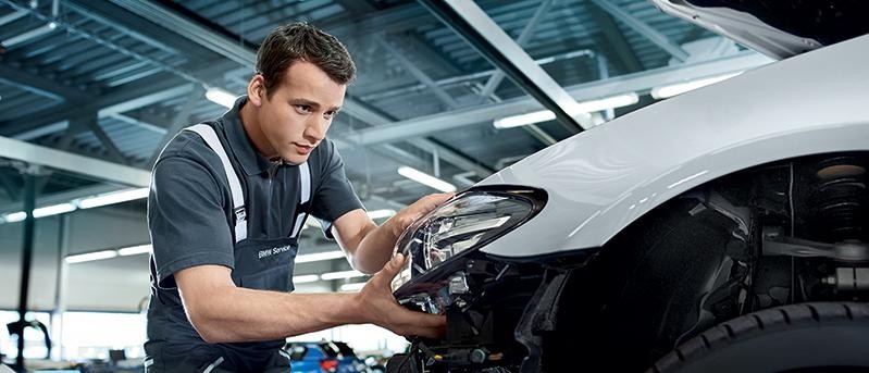 A BMW Certified technician replacing a headlight assembly.
