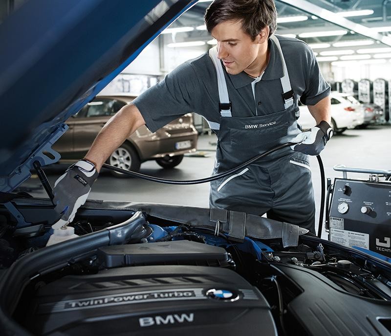 A BMW certified technician topping off a vehicle's fluid levels.