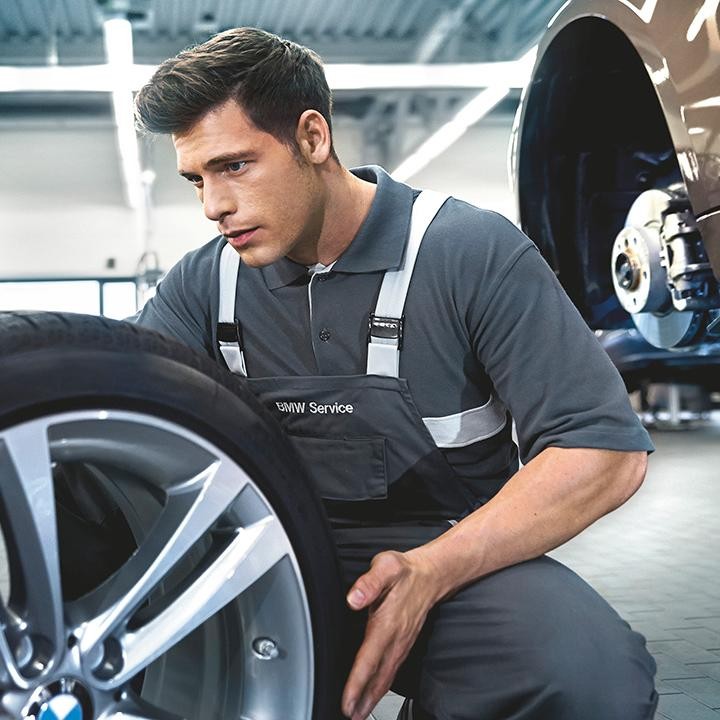 A BMW certified service technician inspecting and rotating tires.