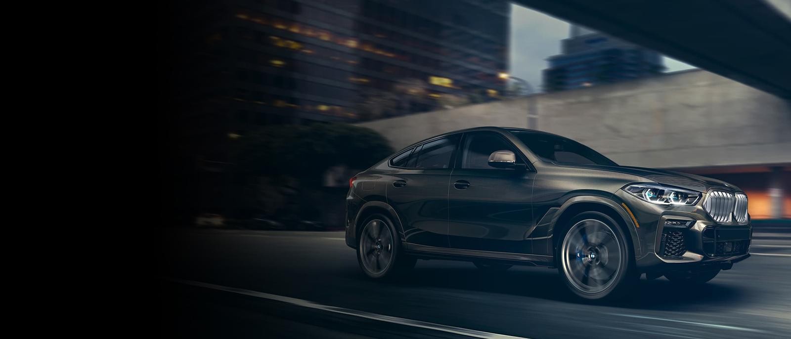 A grey BMW X6 driving along a city street.