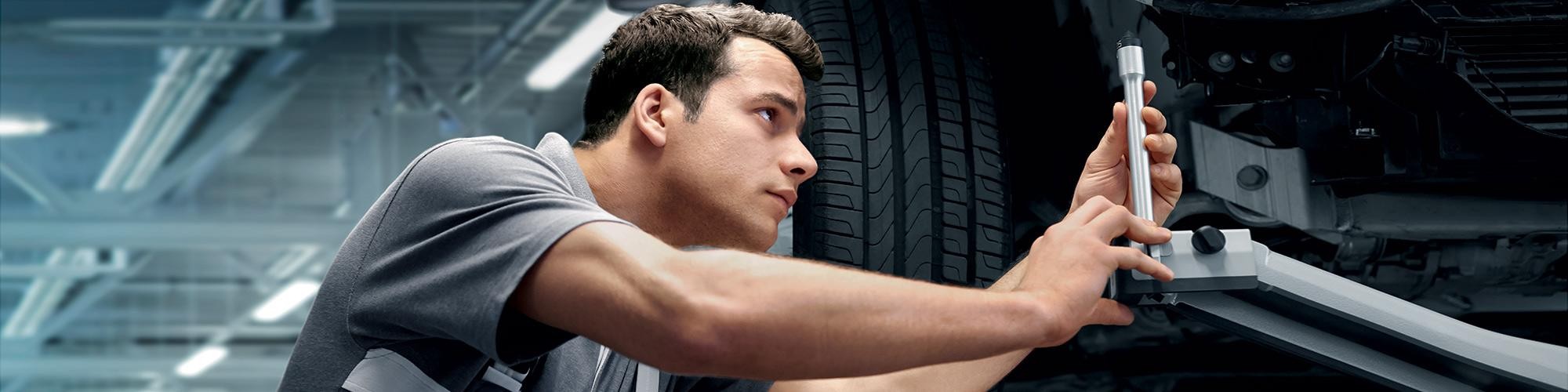 A BMW Certified Service technician working on a vehicle's suspension.
