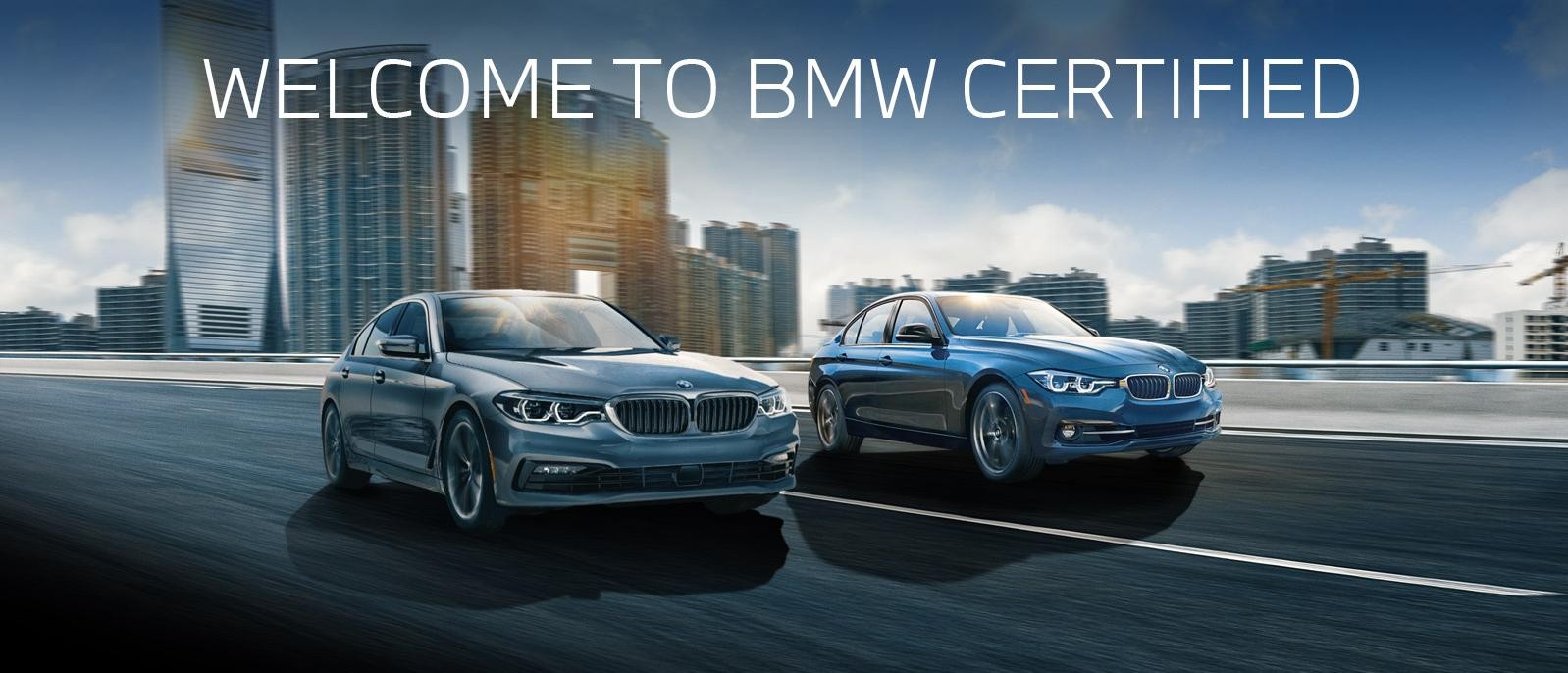 A certified pre-owned grey BMW 5 Series and a blue 3 Series driving down a city freeway.