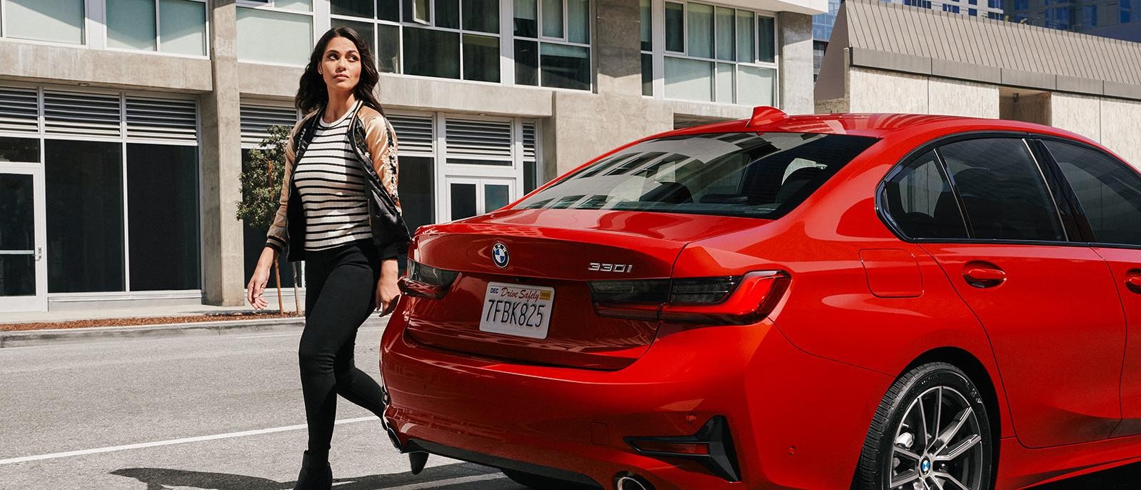 Woman walking around her red BMW 3 Series.