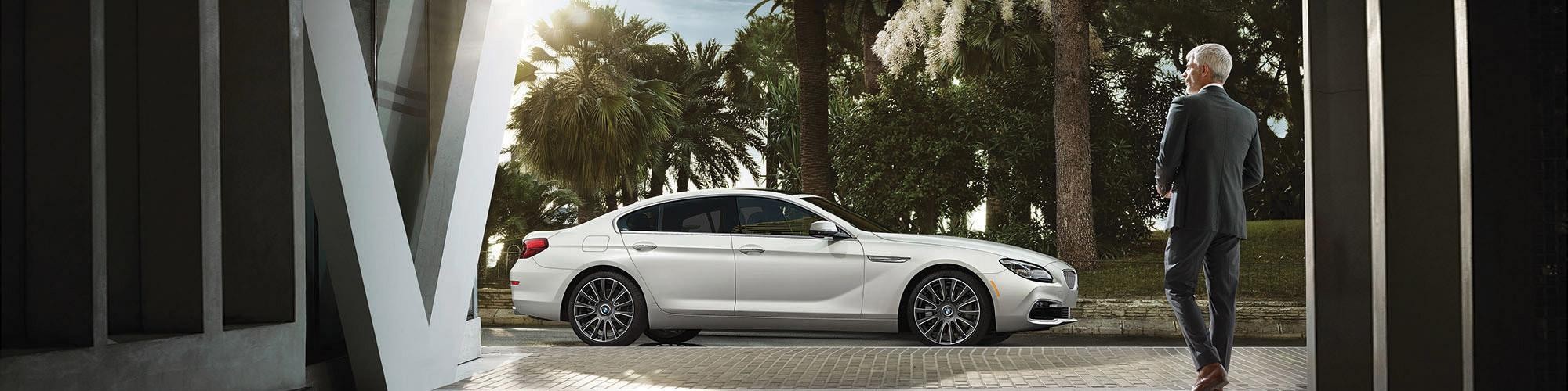 A man walking towards a new BMW 6 Series.