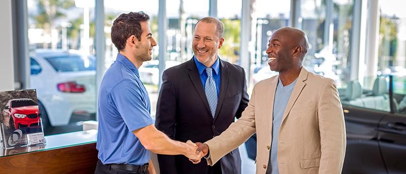 Three men in a BMW showroom introducing themselves.