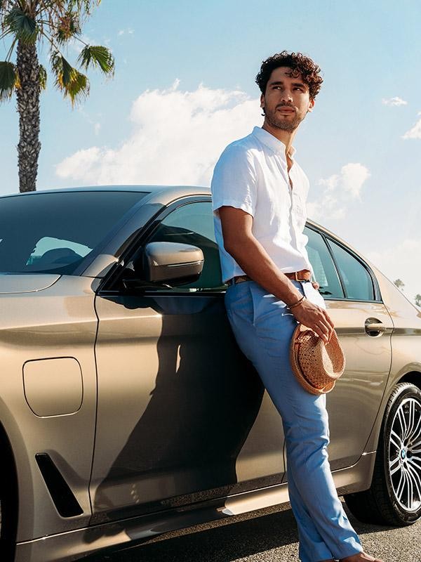 A young man leaning against his new BMW 5 Series.