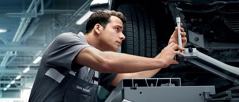 A BMW Certified technician working on a vehicle's suspension.