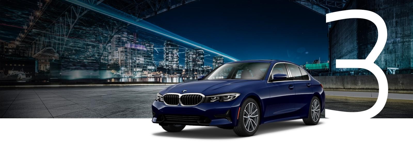 A blue BMW 3 Series parked under a bridge at night.