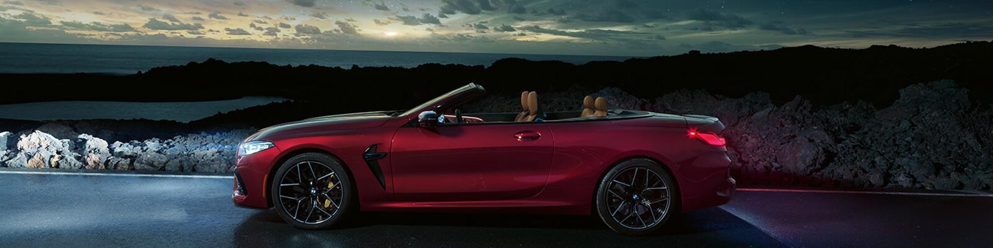 Profile view of a BMW 8 Series Convertible at a coastal overlook at dusk.