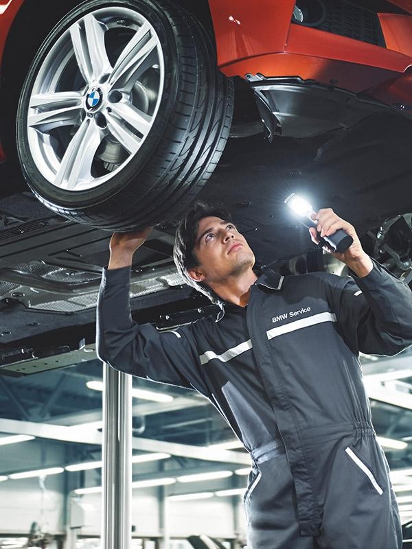 A BMW service technician working under a vehicle.