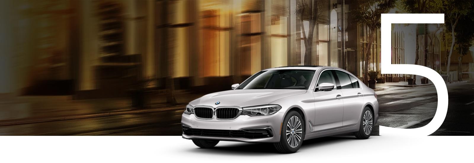 A silver BMW 5 Series on a city street at night.