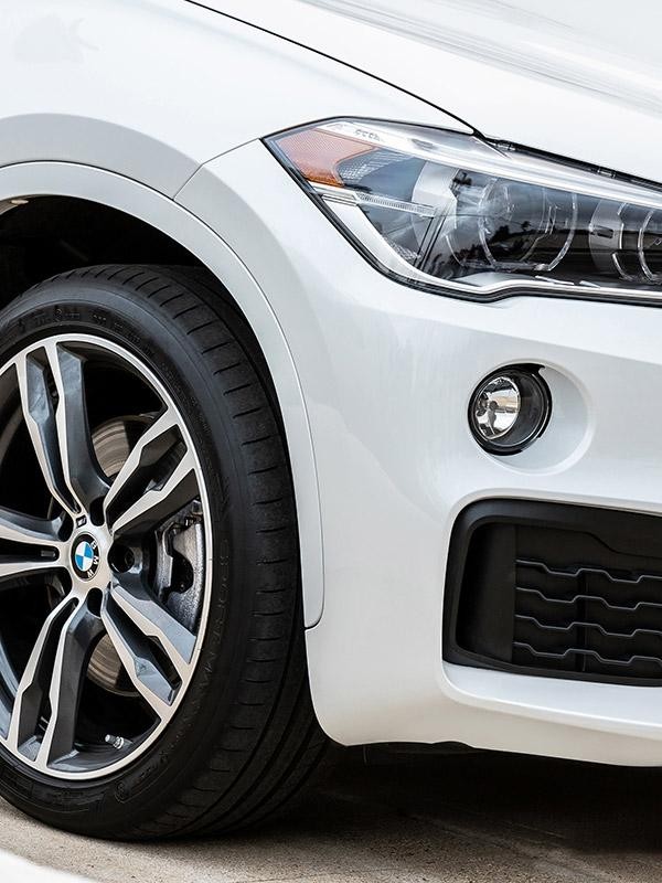 Close-up of a white BMW X1 wheel and headlight.