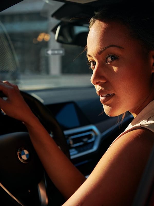 Close-up of a woman in a the driver's seat of a red BMW.