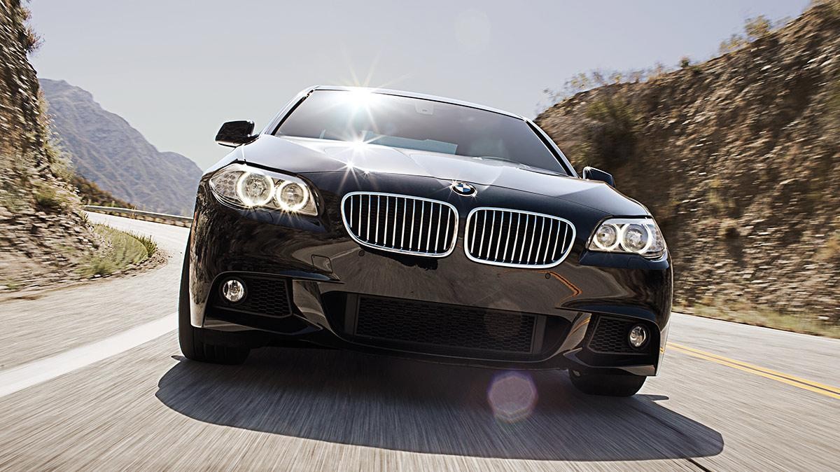 A head-on view of a black BMW on a desert road.