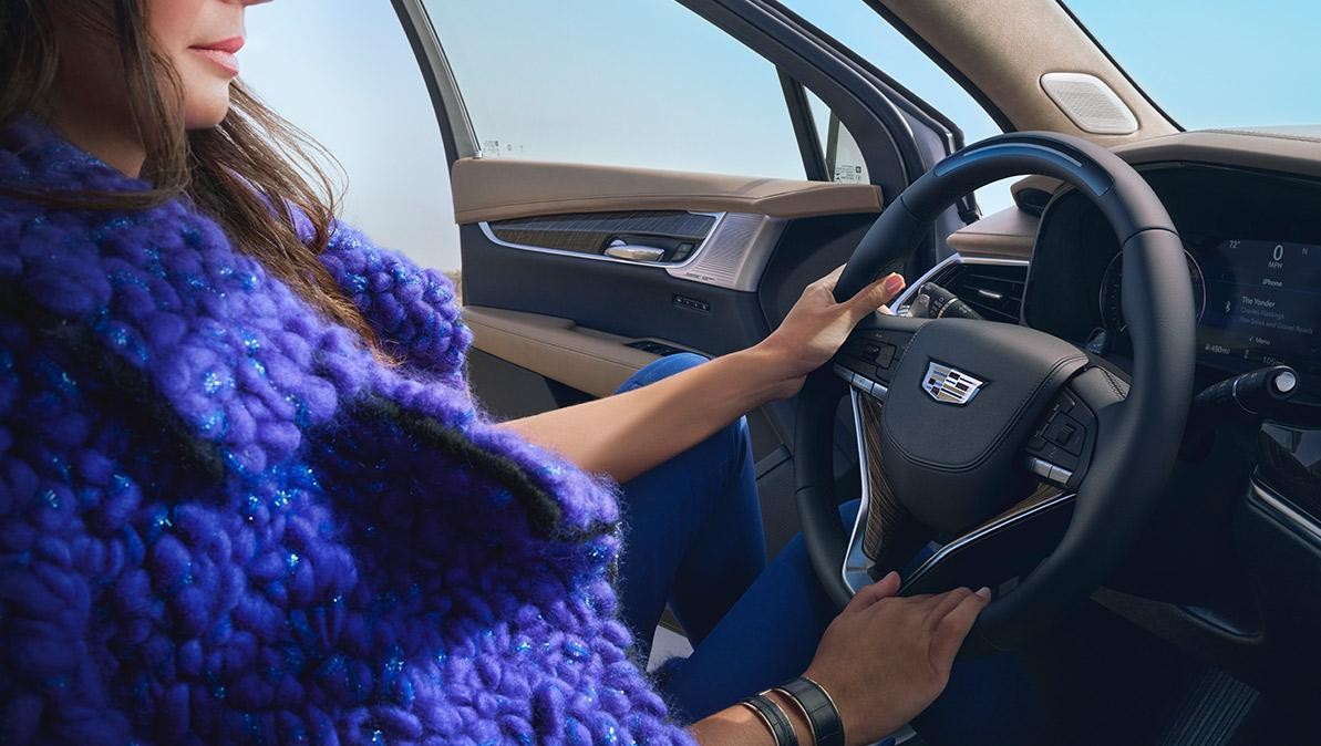 A Woman Uses Both Hands to Hold the Steering Wheel of the Cadillac XT6 A Woman Uses Both Hands to Hold the Steering Wheel of the Cadillac XT6