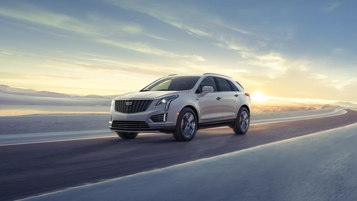 The 2024 Cadillac XT5 Driving on a Winding Road with Sun Rising in Background The 2024 Cadillac XT5 Driving on a Winding Road with Sun Rising in Background