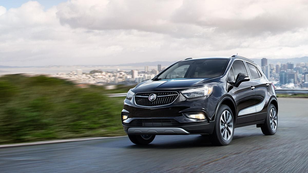 A black Buick Encore driving away from a city.