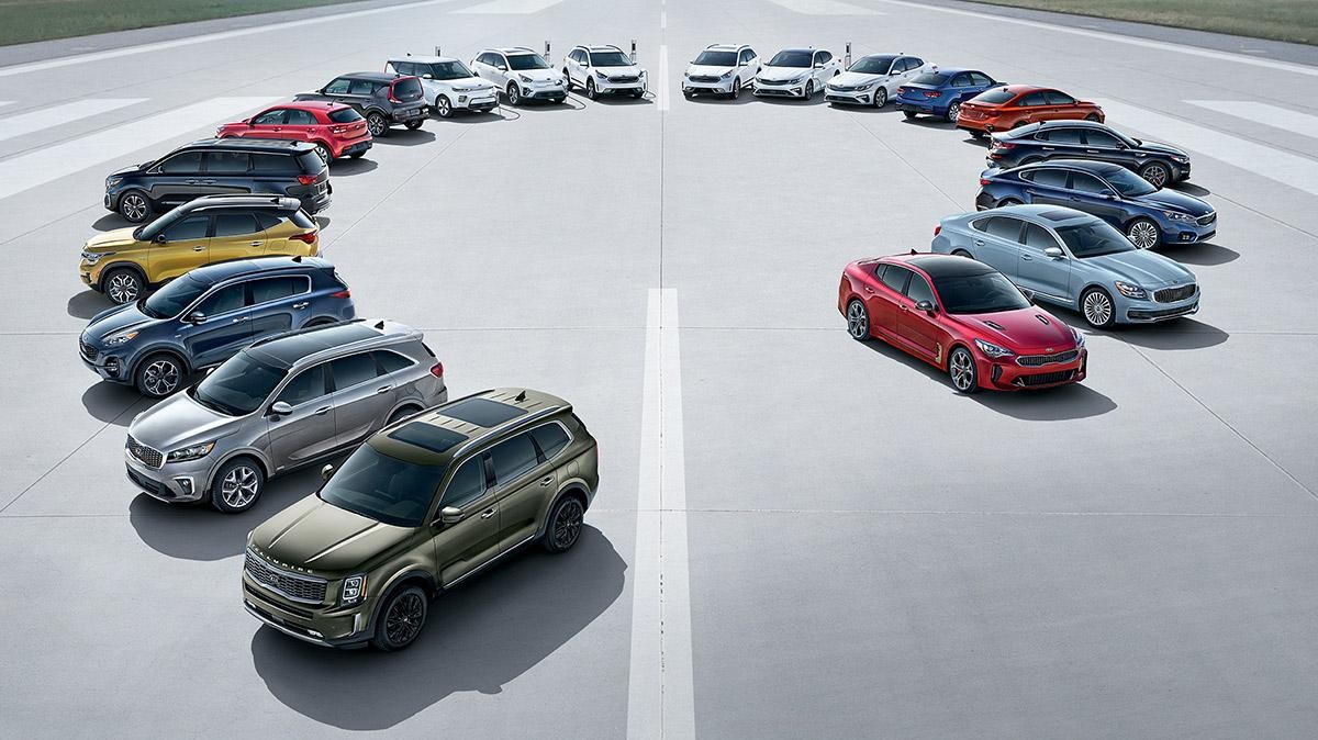 The 2021 Kia vehicle lineup in a semi-circle on an airport runway.