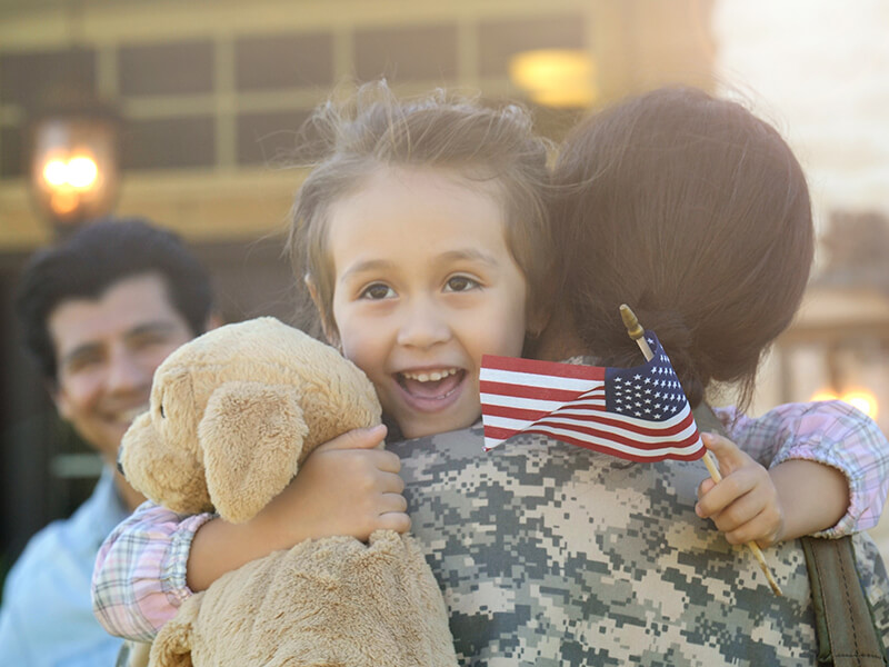 Young girl embracing her military mother