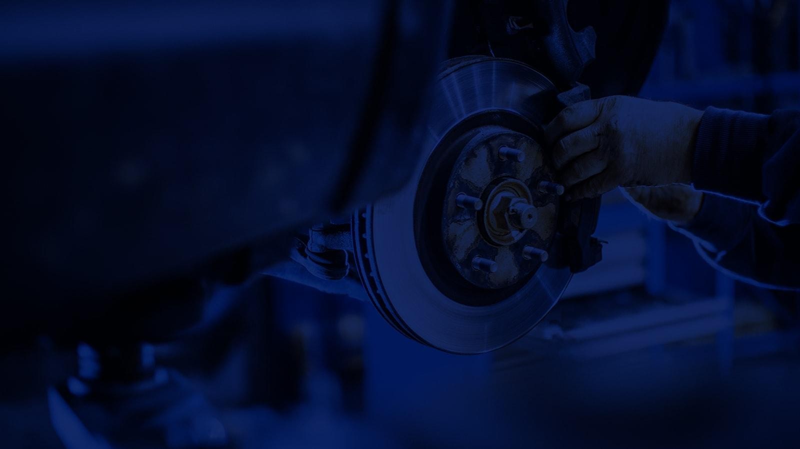 Service mechanic working on a vehicle brake with a blue overlay