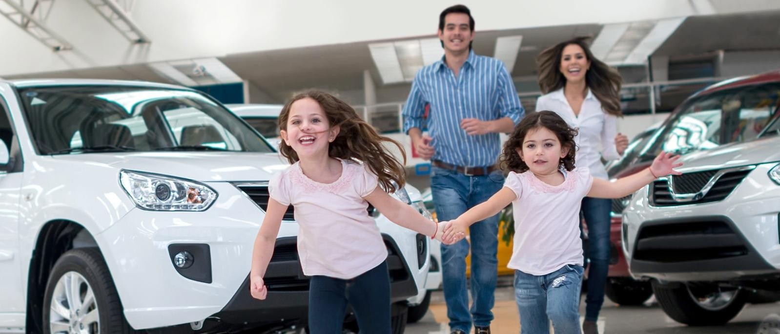 Family with young kids running through a dealership showroom