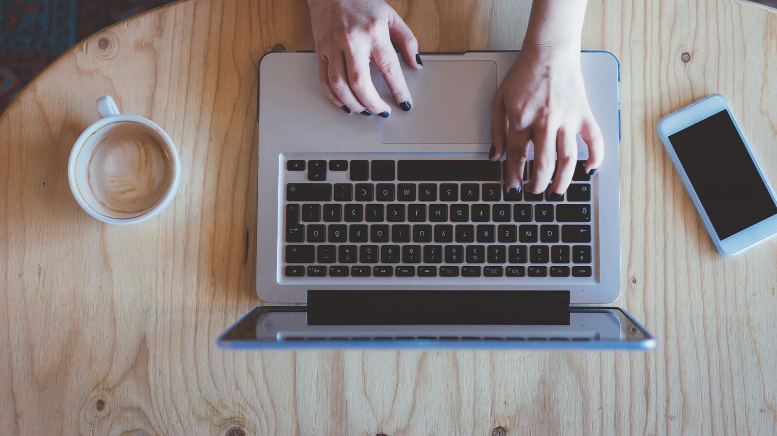 A woman's hands typing on a laptop computer