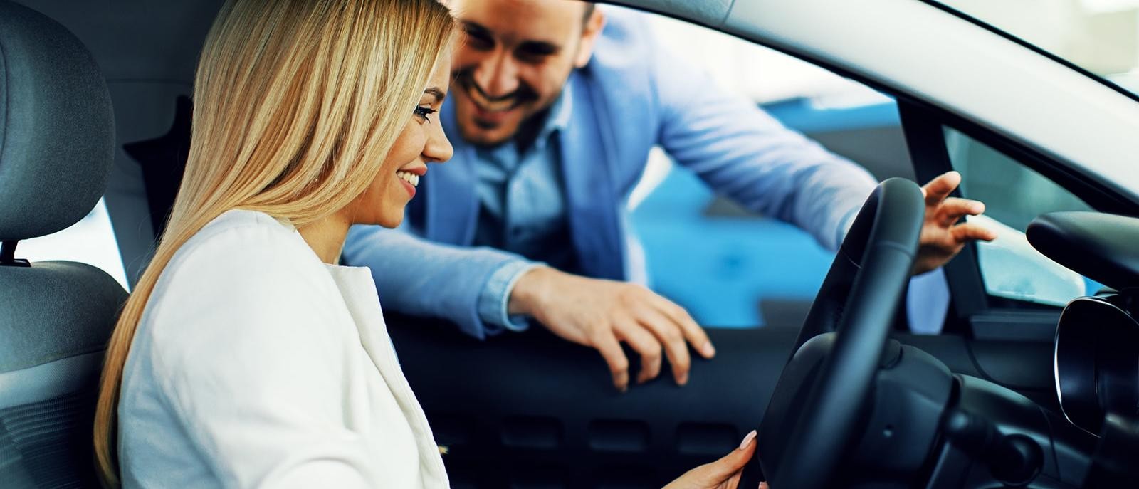 Smiling woman in a dealership sitting in a new vehicle