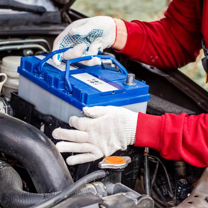 Service technician changing car battery