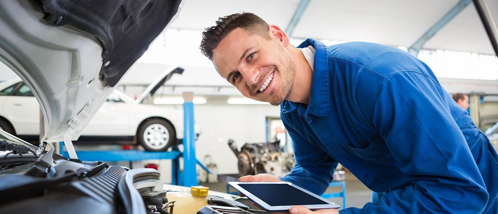 Smiling service mechanic working on an engine