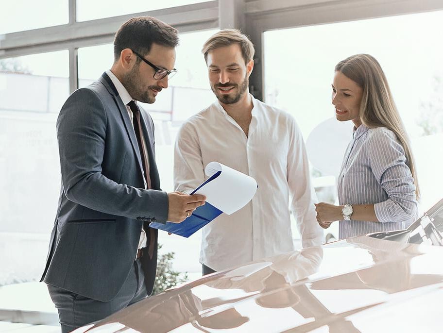 Dealership sales associate helping a smiling couple shop for a new vehicle