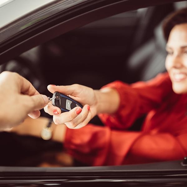 Woman in red taking her new car keys