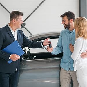 Couple in a dealership with a salesman and car keys
