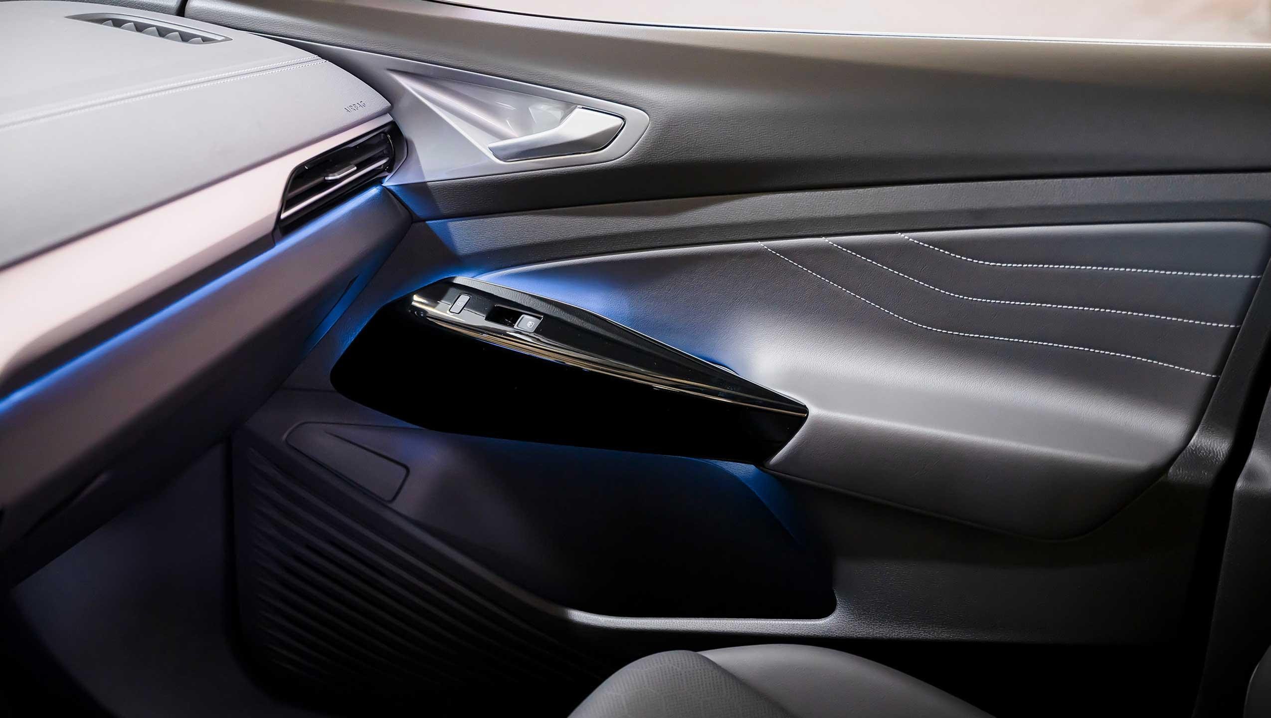 Interior shot of an ID.4 showing multi-colored adjustable ambient lighting on the dash and passenger door handle. 