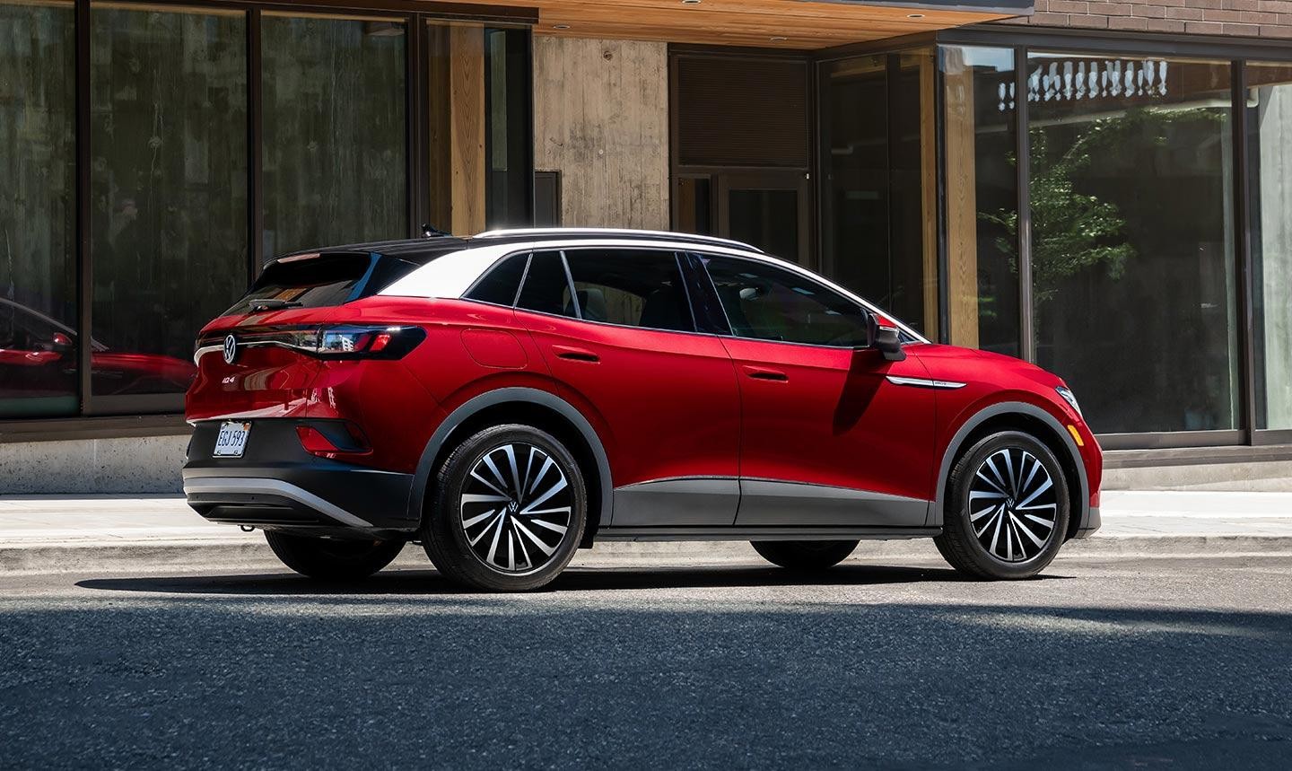 An Aurora Red Metallic ID.4 Pro S Plus parked on an urban street in front of a modern building.