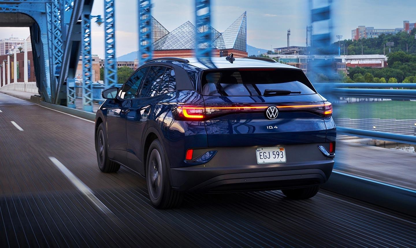 An ID.4 Pro S Standard shown in Tourmaline Blue Metallic drives through a bridge at dusk.