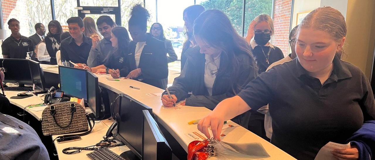 Savannah Arts Academy students in a line to pick up their Vaden Automotive name tags in front lobby area
