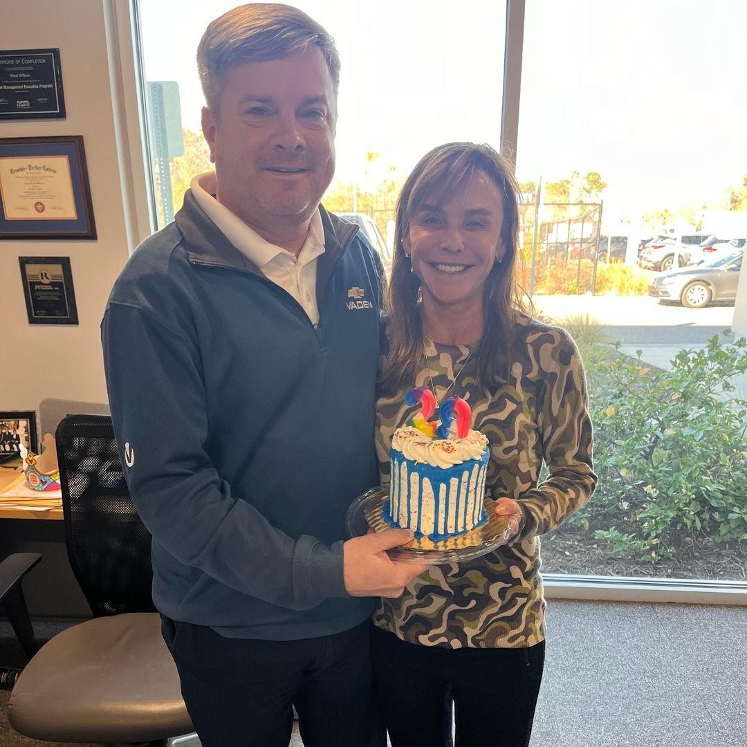 GM, Neal Wilson and Vaden Automotive President, Jane Vaden Thacher, both holding cake while smiling. 