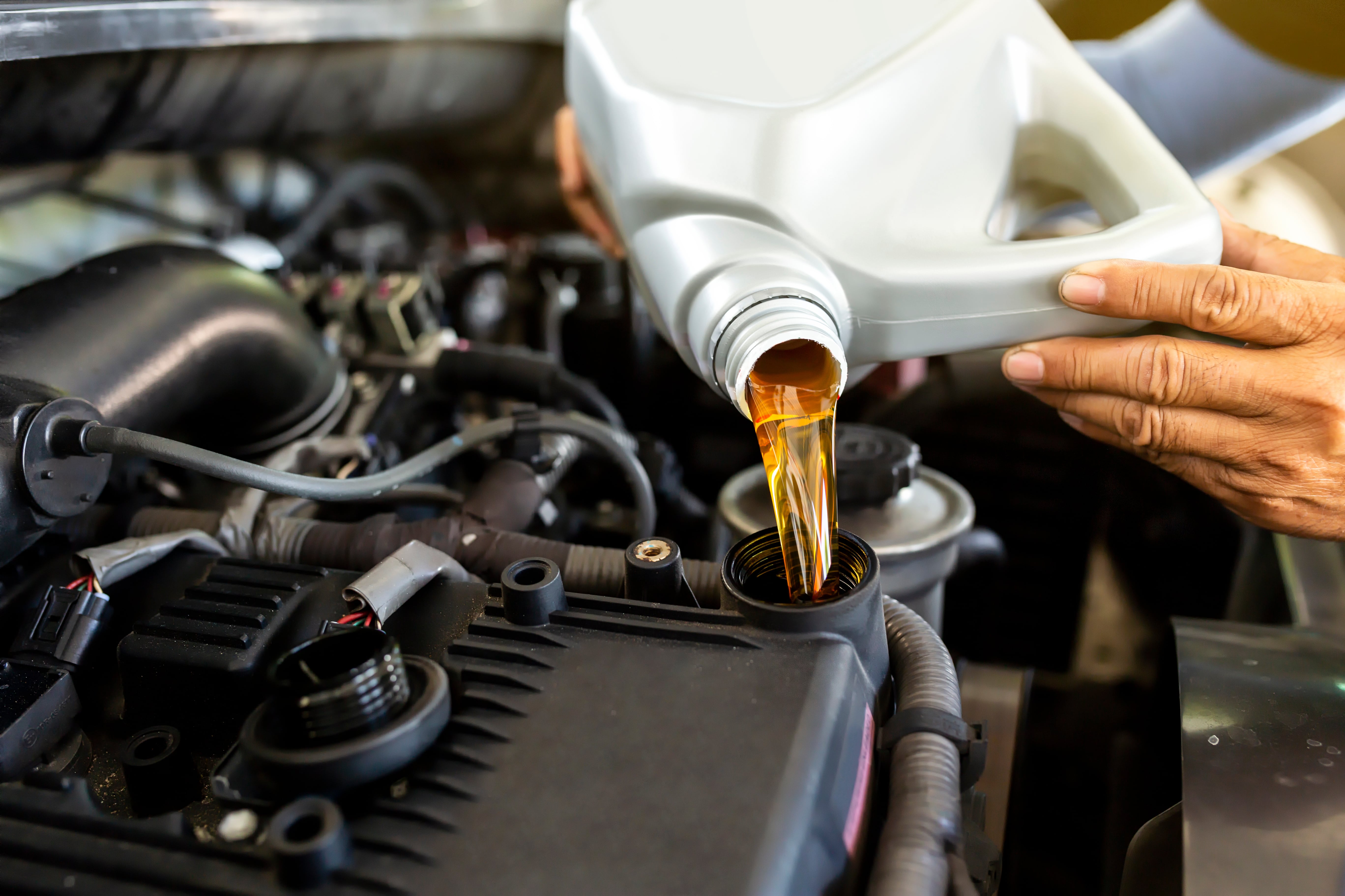 mechanic adding oil to a 2025 GMC Acadia