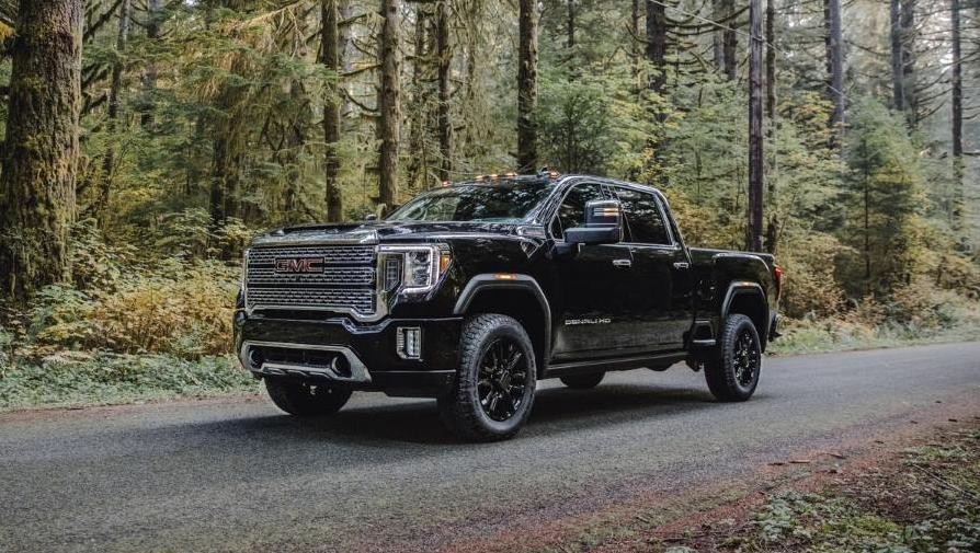 2023 GMC Sierra Denali 2500HD Crew Cab Standard Box with in Ebony Twilight Metallic with 20" High Gloss Painted Black Aluminum Wheels; 3/4 Drivers side Front; Forest background. 
