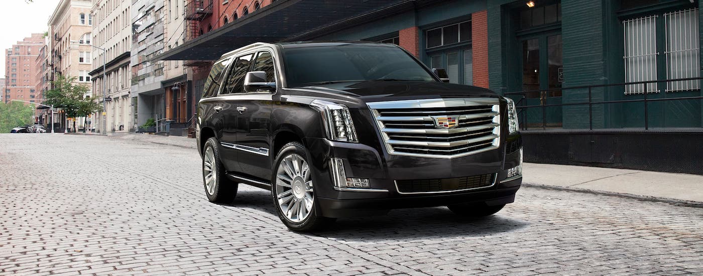 A popular used Cadillac for sale around Fort Worth, a black 2018 Cadillac Escalade, is parked on a city street.