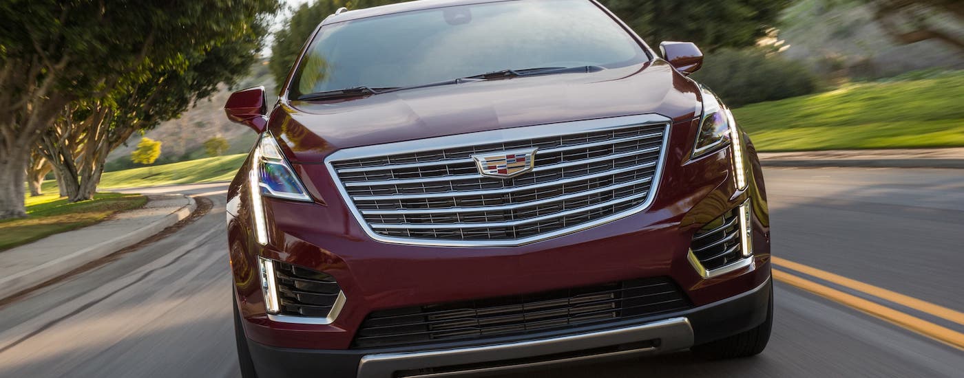 A great find for a used Cadillac for sale in Fort Worth, a red 2019 Cadillac XT5 Platinum, is shown driving on a highway from the front.